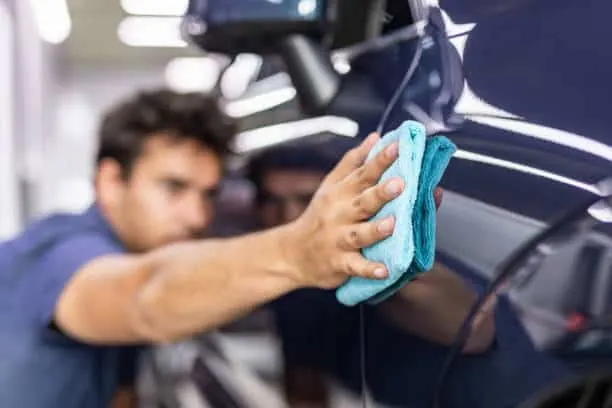 Detailer wiping down vehicle paint with a microfiber towel during a maintenance detail in San Diego